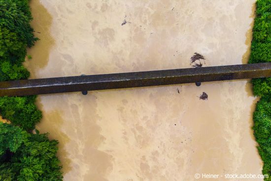 Luftaufnahme einer alten Brücke über einem mittelgrossen Fluss mit Hochwasser